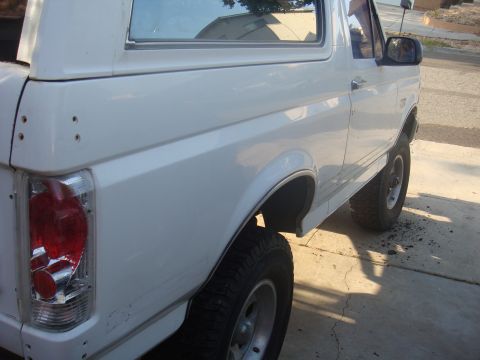 1992 Ford Bronco - Side view of a white 1992 Ford Bronco, showing the rear quarter panel and wheel.