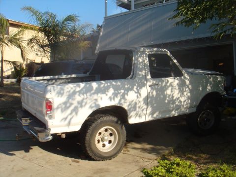 1992 Ford Bronco - A white pickup truck is parked in a driveway, partially shaded by trees.