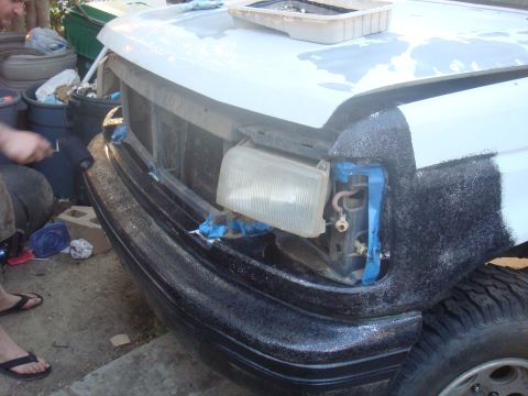 1992 Ford Bronco - The front of a 1992 Ford Bronco is shown with its bumper and headlight area being worked on, indicating a repair or restoration process.
