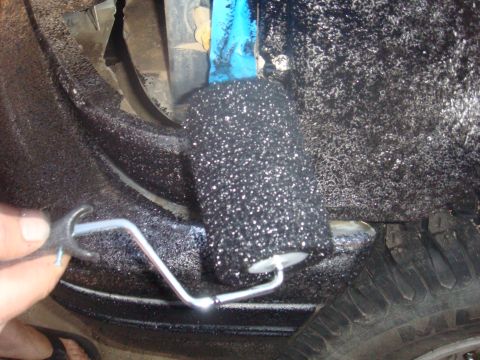 1992 Ford Bronco - Applying protective undercoating to the wheel well of a vehicle with a roller.