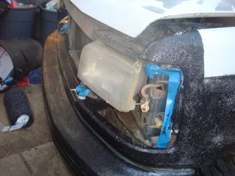 1992 Ford Bronco - The front of a vehicle is shown with the headlight assembly removed and taped in place.
