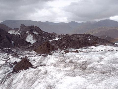 1996 Ford Bronco - A vast glacial landscape unfolds, dark moraine deposits contrasting with the white ice, all under a dramatic, cloudy sky.