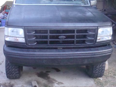 1992 Ford Bronco - The front grille and bumper of a black 1992 Ford Bronco are visible, with large tires on either side.