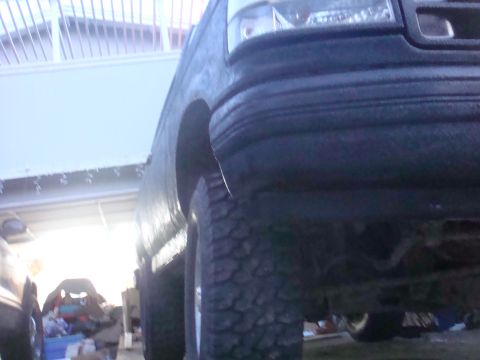 1992 Ford Bronco - Low-angle view of a Ford truck's front wheel and fender, showing off its off-road tires.