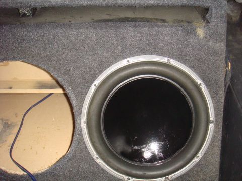 1992 Ford Bronco - Close-up view of a carpeted car subwoofer enclosure, showing one speaker and an empty cutout with wiring.