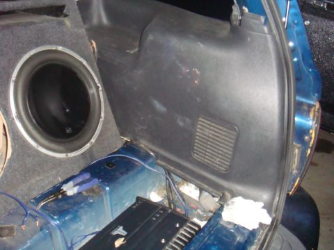 1992 Ford Bronco - The interior cargo area of a blue vehicle shows a large subwoofer and amplifier, with visible wiring and modifications.