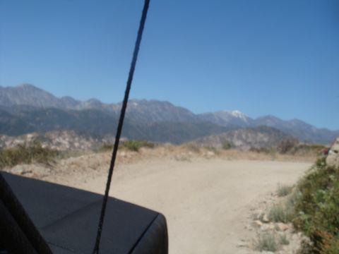 1992 Ford Bronco - View from inside a vehicle driving on a dirt road with mountains in the distance.