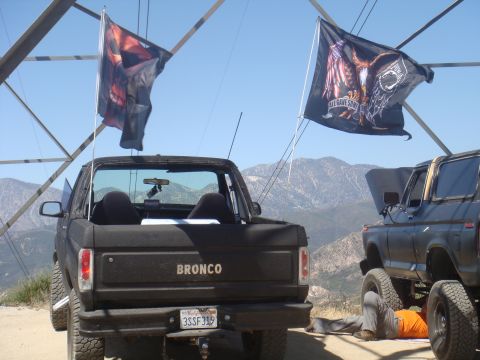 1992 Ford Bronco - Two Ford Broncos are parked on a hill, one with its hood open, under a clear sky.