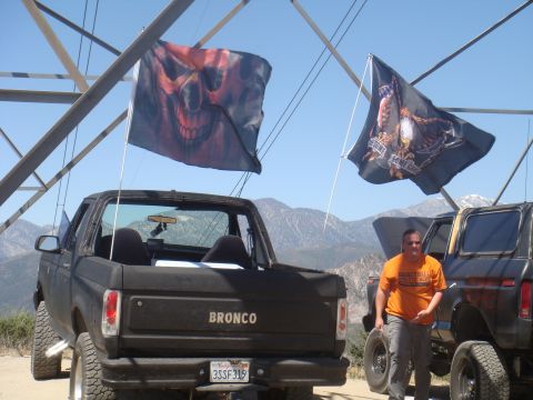 1992 Ford Bronco - Two Broncos are parked outdoors with flags flying, one with a skull design and the other with an eagle.