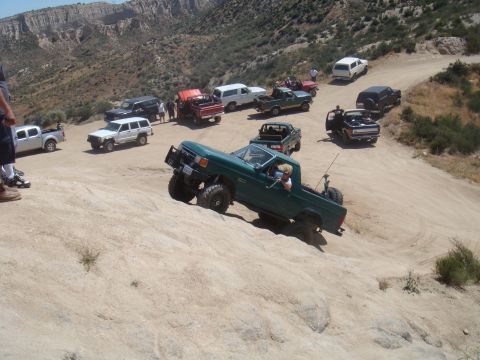 1992 Ford Bronco - Several off-road vehicles navigate a steep, sandy trail in a mountainous area.