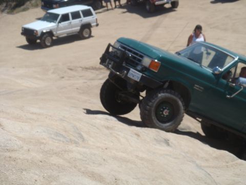 1992 Ford Bronco - Green Ford Bronco navigating an off-road trail with a white SUV visible in the distance.