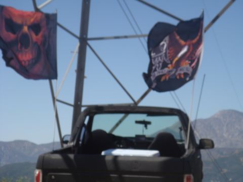 1992 Ford Bronco - A black 1992 Ford Bronco is parked outdoors with two flags flying from a pole behind it.