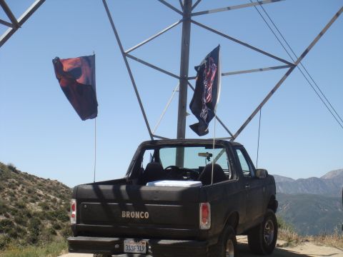 1992 Ford Bronco - Rear view of a black 1992 Ford Bronco parked outdoors with two flags attached to poles.