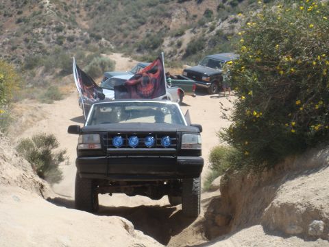 1992 Ford Bronco - A black 1992 Ford Bronco leads a convoy of off-road vehicles on a dusty trail, adorned with skull flags.
