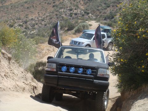 1992 Ford Bronco - A black 1992 Ford Bronco navigates a dusty off-road trail with other vehicles following behind.