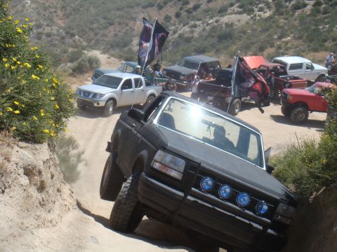 1992 Ford Bronco - A group of off-road vehicles navigate a dusty trail under a bright sun.