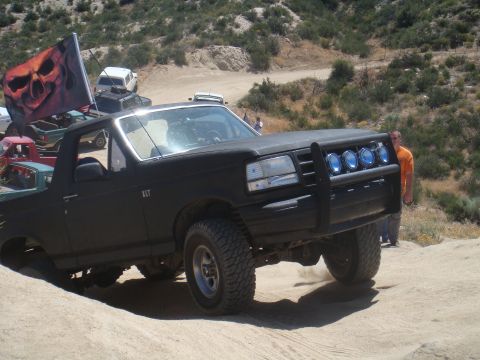 1992 Ford Bronco - A black 1992 Ford Bronco is seen off-roading with a skull flag attached.