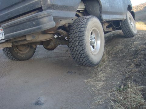 1992 Ford Bronco - The rear suspension and off-road tires of a vehicle are shown on a dirt path.