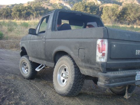 1992 Ford Bronco - This 1992 Ford Bronco is shown from the rear quarter angle on a dirt road with hills in the background.