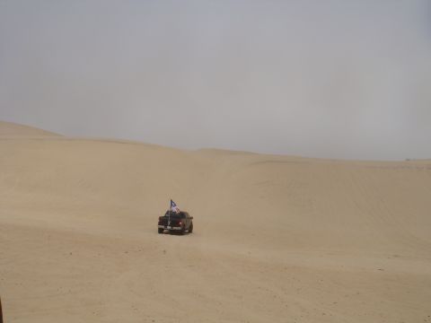 1992 Ford Bronco - A lone truck navigates a vast sandy landscape, its flag fluttering in the distance.