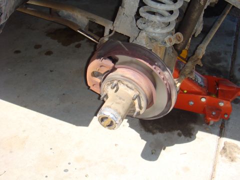 1992 Ford Bronco - Close-up view of a vehicle's rear axle and brake assembly, supported by an orange jack.