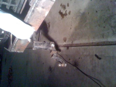 1992 Ford Bronco - A trailer hitch assembly is shown attached to a concrete wall, with a light bulb hanging from a wire.