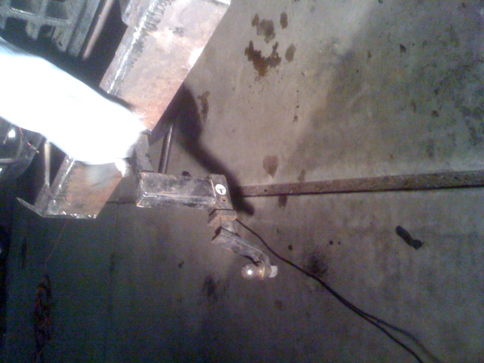 Trailer hitch assembly attached to a concrete wall, with a light bulb visible
