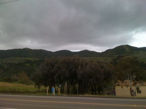 1992 Ford Bronco - A cloudy day over rolling hills and a roadside view with a small building.