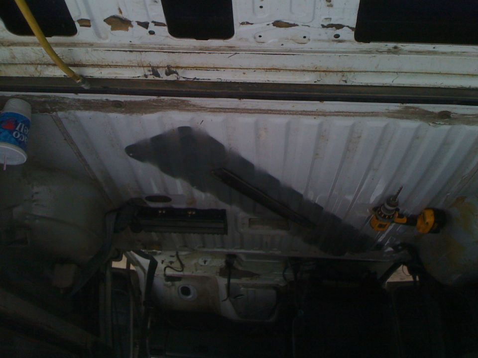 Interior underside of a vehicle with a drill and a can of spray