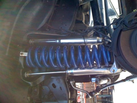 1992 Ford Bronco - Vehicle suspension system with blue coil springs and shiny shock absorbers.