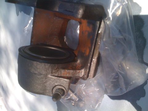 1992 Ford Bronco - A close-up view of a rusty brake caliper part, partially covered by plastic.