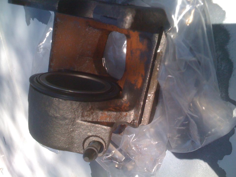 Brake caliper part, possibly for an older vehicle. It's rusty and in plastic packaging