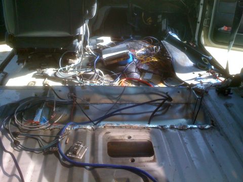 1992 Ford Bronco - The interior of a vehicle is shown with the floor stripped bare and a complex network of wires exposed.
