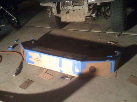 1992 Ford Bronco - A cardboard mockup of a bumper is taped together and placed on the ground in front of a vehicle's chassis.