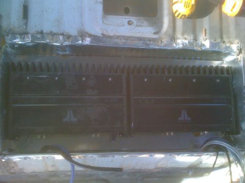 1992 Ford Bronco - Two JL Audio amplifiers are mounted in the cargo area of a vehicle, showing custom metalwork and wiring.