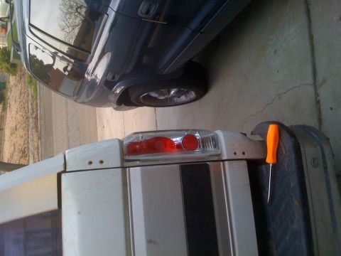 1992 Ford Bronco - A white truck and a dark SUV are parked next to each other on a concrete surface.