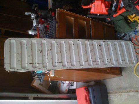 1992 Ford Bronco - A weathered white tailgate with a ribbed surface is shown, with tools and storage in the background.