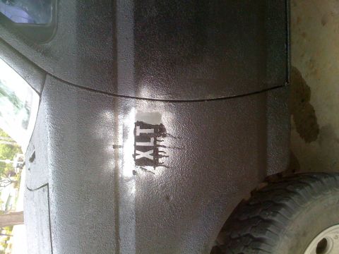 1992 Ford Bronco - Close-up of the XLT emblem on a 1992 Ford Bronco, showing the textured paint finish.