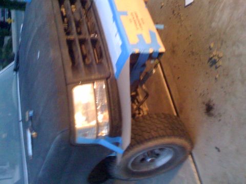 1992 Ford Bronco - The front end of a Ford Bronco is visible, with the hood up and some blue tape applied to the grille area.