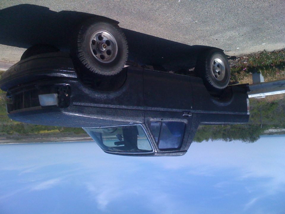 Black pickup truck, side view, with textured paint and aftermarket wheels