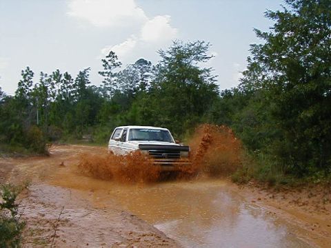 1990 Ford Bronco - This 1990 Ford Bronco is navigating a muddy trail, sending water and dirt flying.