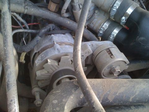 1992 Ford Bronco - This image shows engine components, including an alternator and various hoses, in a dirty engine bay.