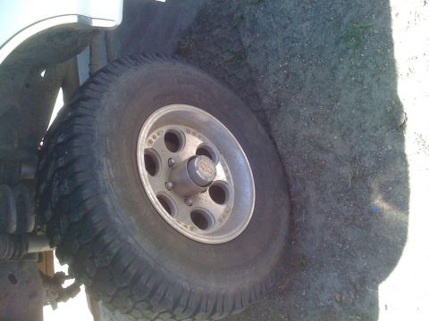 1992 Ford Bronco - A close-up view of a vehicle's wheel and tire, with the ground visible around it.