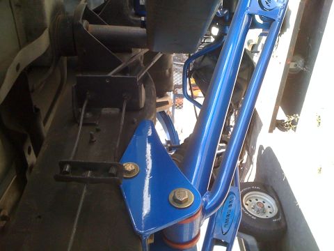 1992 Ford Bronco - Close-up of custom blue suspension components installed on a vehicle's frame.