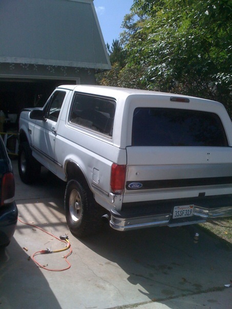1992 Ford Bronco - This white Ford Bronco is parked in a driveway next to a garage. The rear of the vehicle is visible.
