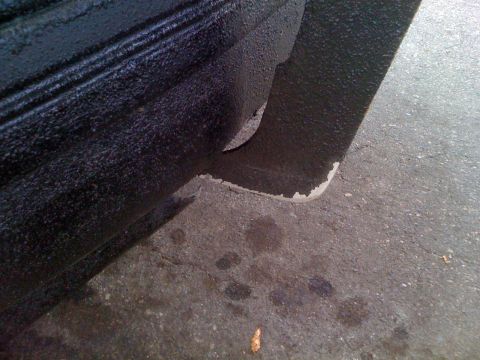 1992 Ford Bronco - Close-up of a vehicle's wheel well liner shows wear and tear on the black textured surface.