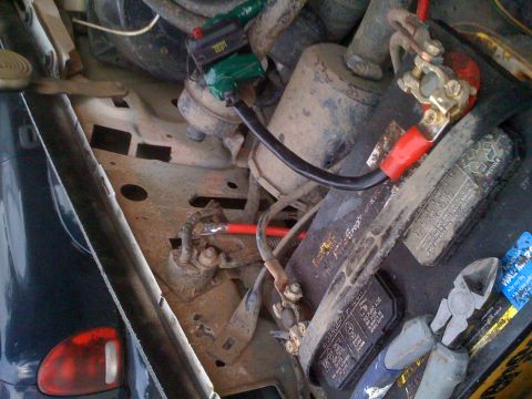 1992 Ford Bronco - Close-up view of the engine bay, focusing on the battery, wiring connections, and a green fuse holder.