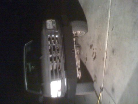 1992 Ford Bronco - The front grille and headlight of a 1992 Ford Bronco are visible in this image, showing a portion of the vehicle's front end.