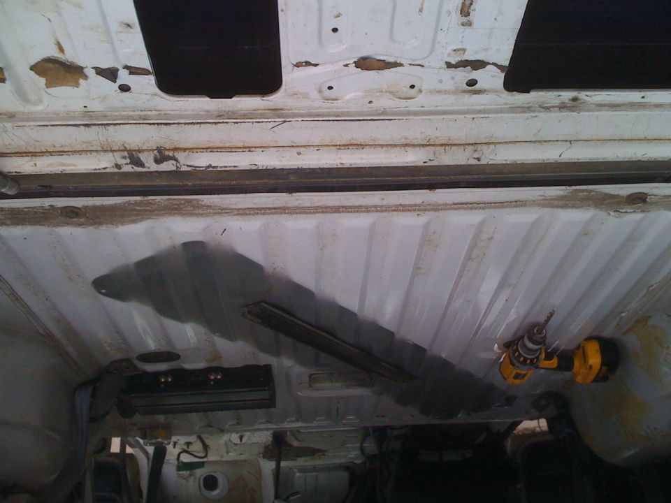 Drill working on the underside of a white vehicle