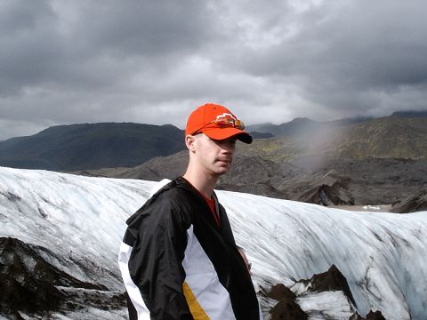 1996 Ford Bronco - A man stands on a glacier under a dramatic, cloudy sky, with mountainous terrain in the background.